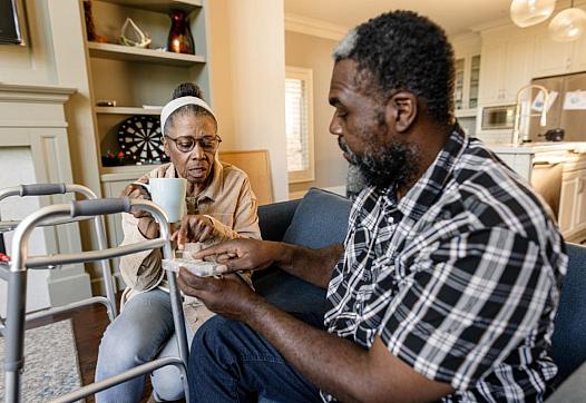 2 people discussing, one holding a medicine box