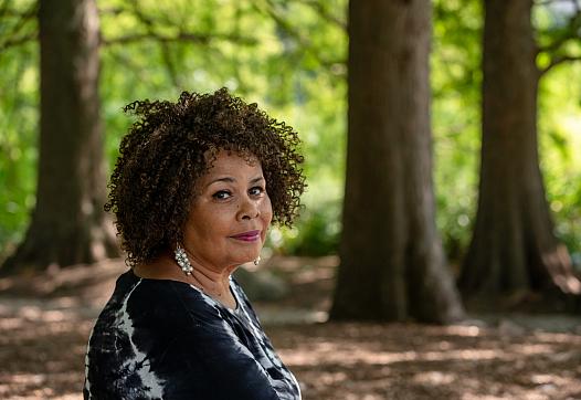 Image of a black woman sitting in front of trees
