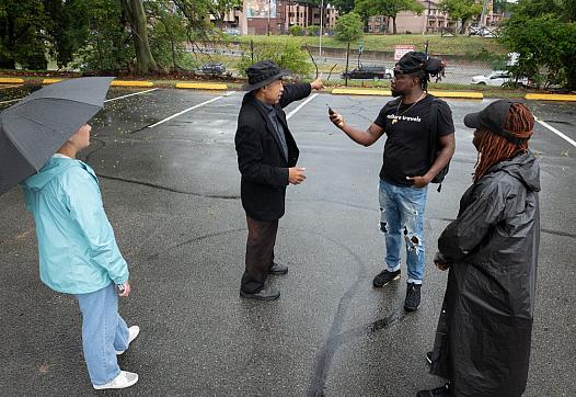 Person speaking into mic held by another person, as 2 more watch