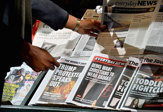 Image of person taking newspaper from newspaper stand.