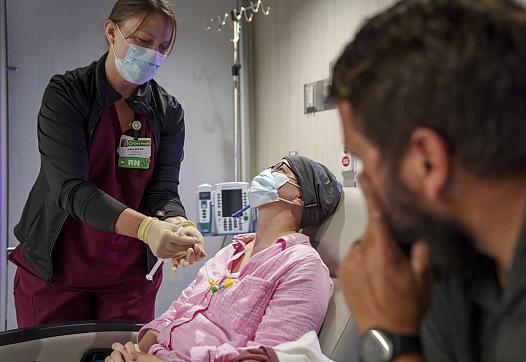 A nurse administrating medicines to a patient while a visitor watches