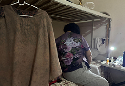 A person sitting on a bed facing away