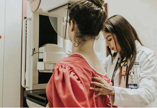 A female doctor helps another woman get a mammogram