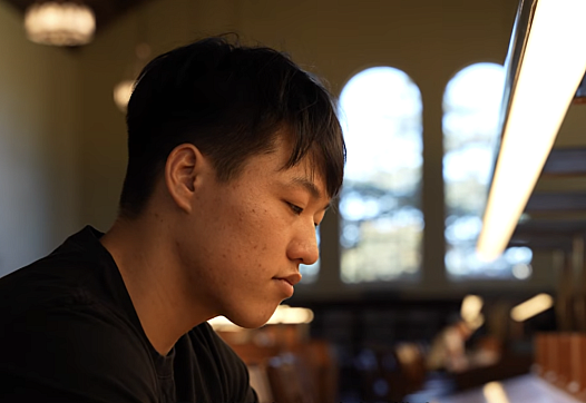 A young Korean man sits in a library