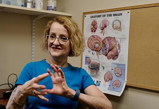 A lady trying to explain something in front of a brain diagram