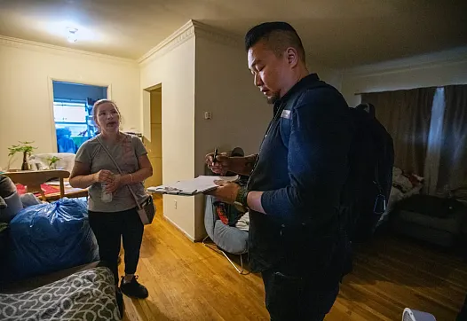 A mental health professional taking notes while talking to a distressedlady