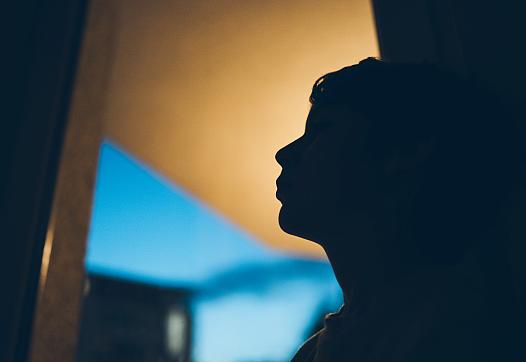 Teen silhouetted in a room.