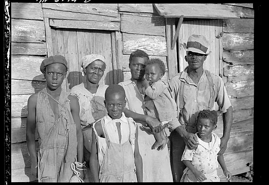 Multiple people standing in front of a wooden hut