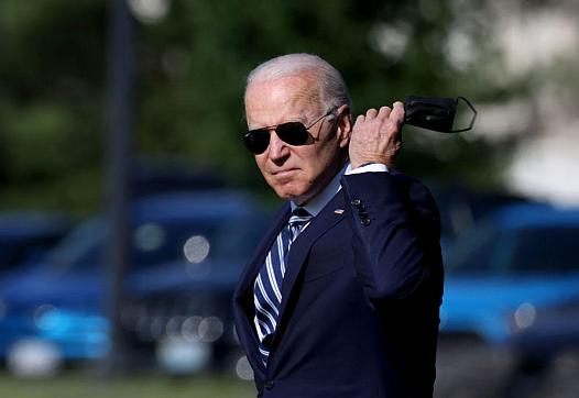 President Joe Biden looking in a camera with mask in his hand