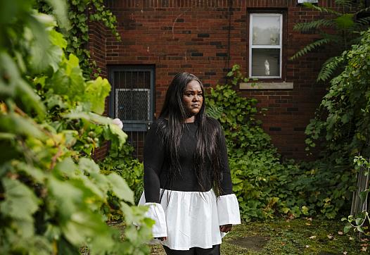 A person in black and white dress standing against a tree