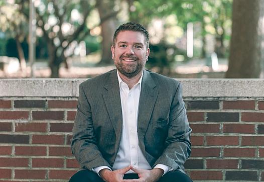 A man sitting against a wall, smiling