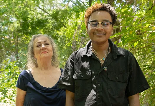Two people standing next to each other in greenary