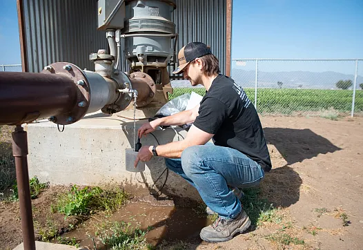 Person working on a farm and collecting water from pipe