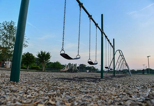 Multiple swings installed in an open playground against a bright blue sky