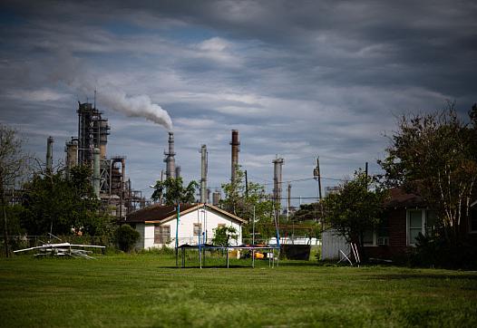 An independent house with a green grass lawn with industrial chimneys in the background