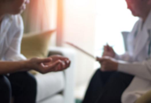 A doctor with a clipboard talks to a patient.