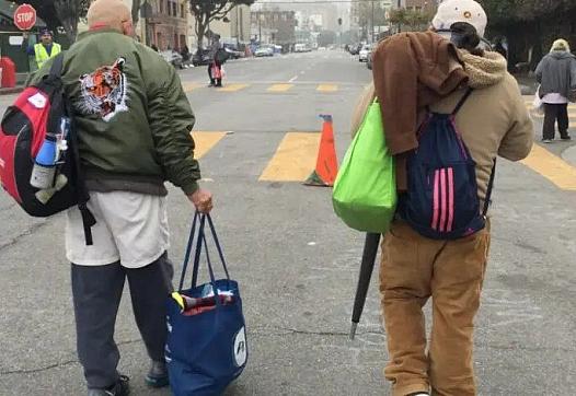 Two people walking on a street with their bags