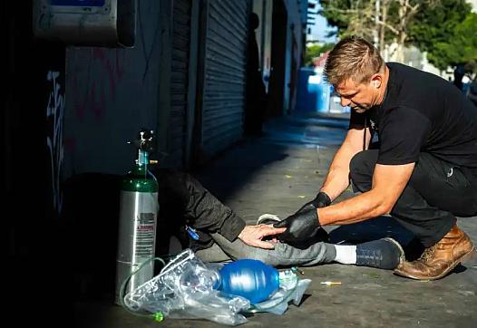 Image of a person checking a homeless person on street