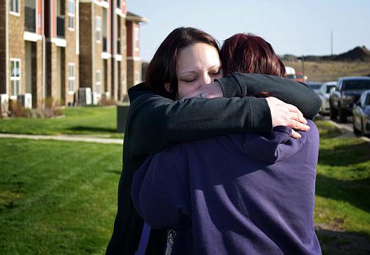 Person hugging another person against a green lawn