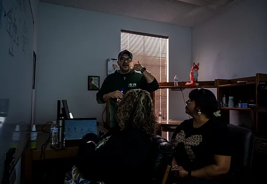Tres personas en una habitación, una de ellas dando una presentación breve a las otras dos.