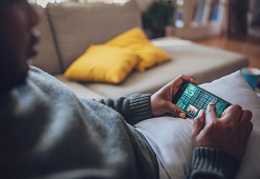 Person holding a mobile phone with a game betting screen on