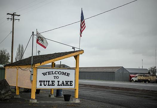 Welcome sign and 2 American flags by a road