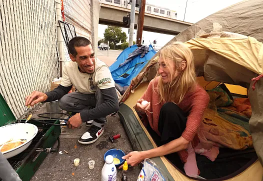 Two people preparing breakfast on street