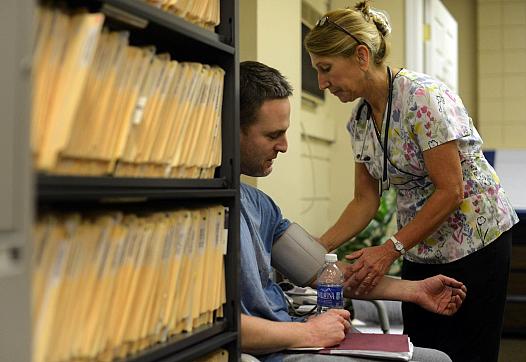Judy Kunes, an LPN and volunteer at the 9th Street Free Clinic in McKeesport, measures the blood pressure of Nathan Hite, a former McKeesport firefighter experiencing shoulder and hip pain, on May 15, 2014. 