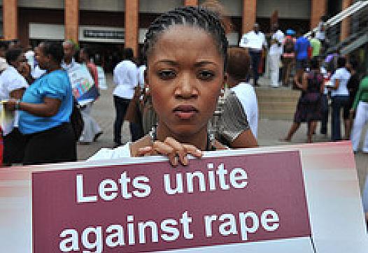 Black woman with sign that reads, "Let's unite against rape."