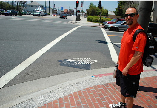 Glendale PLACE Grant Coordinator Colin Bogart shows off the new tri-lingual pedestrian safety markings at an intersection adjace