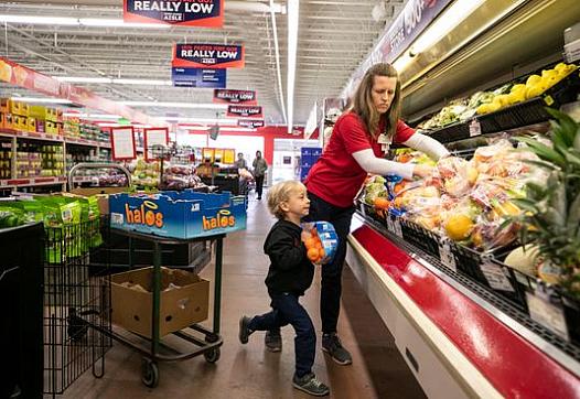 Jenny Kute and four-year-old son Henry put out fresh produce at the family's Save-A-Lot on Taylor Boulevard in the Hazelwood nei