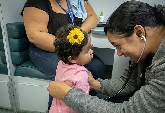 Dr. Raquel Figueras, a pediatrician, listens to toddler Siulaidali Morales’ heart and lungs during a medical exam.