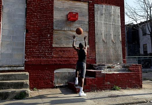 A boy shoots a basketball into a makeshift basket made from a milk crate and attached to a vacant row house in Baltimore, April 8, 2013. Patrick Semansky/AP Photo