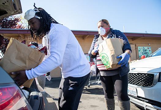 Will Preston and Lene Lauese, staff members at Ecumenical Hunger Program, put bags of produce in a client's car at drive thr