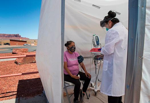 A nurse checks vitals on a Navajo woman complaining of virus symptoms at a COVID-19 testing center in Monument Valley, Arizona i