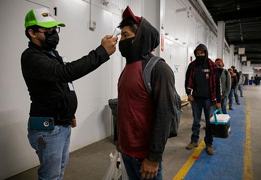 Migrant farm laborers have their temperature checked before boarding a bus to their shift in King City, California in April 2020