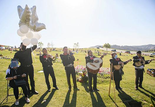 Rosa Mejia (L) listens as a mariachi band plays during a burial service for her husband Gilberto Arreguin Camacho, 58