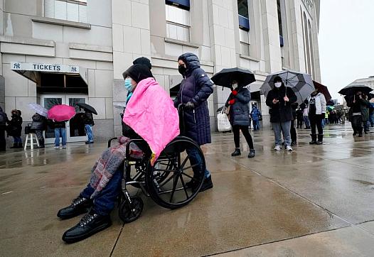 People line up in the rain outside the Yankee Stadium on February 5, 2021 in New York as the Stadium is turned into a mass Covid