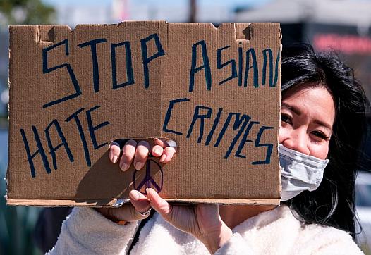 A demonstrator wearing a face mask and holding a sign takes part in a rally to raise awareness of anti-Asian violence