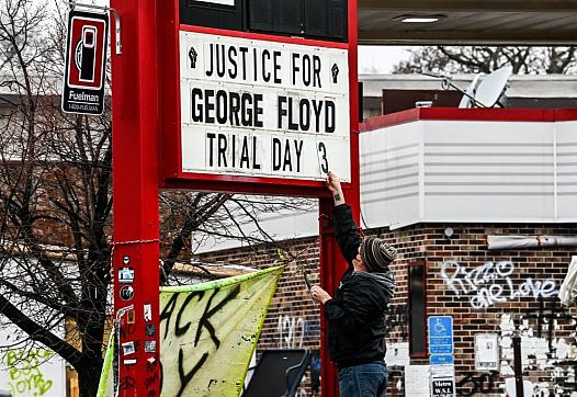 A man changes the number of a sign board at a makeshift memorial of George Floyd before the third day of jury selection begins i