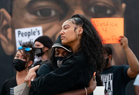 Two women embrace in front of a mural of George Floyd following the guilty verdict the trial of Derek Chauvin