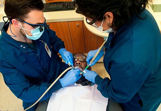 Dr. Luke Johnson (L) and dental assistant Rita Garcia treat patient Phillip Malone at Inner City Health Center in Denver, CO. 