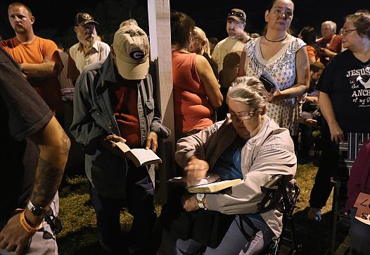 People read the bible while waiting to get free health care services at a mobile clinic in Wise, Virginia. (Photo by John Moore/