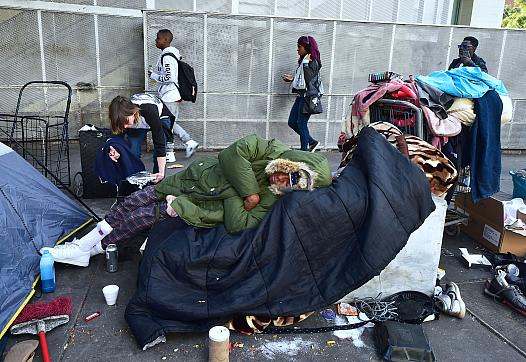 Homeless woman Caroline Francis places a platter of food for her neighbor on the street in downtown Los Angeles shortly before C