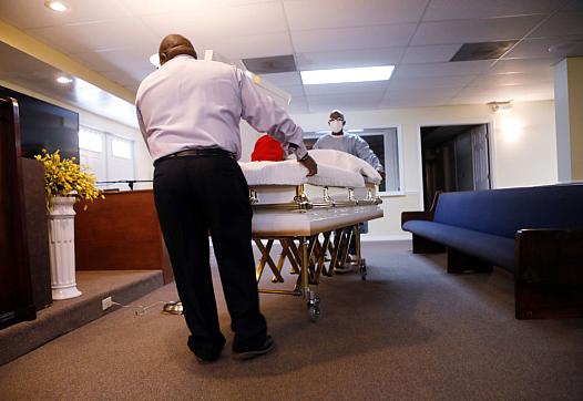 A mortician assistant and embalmer prepare a funeral service for a man who died in August of COVID-19 at Ray Williams Funeral Ho