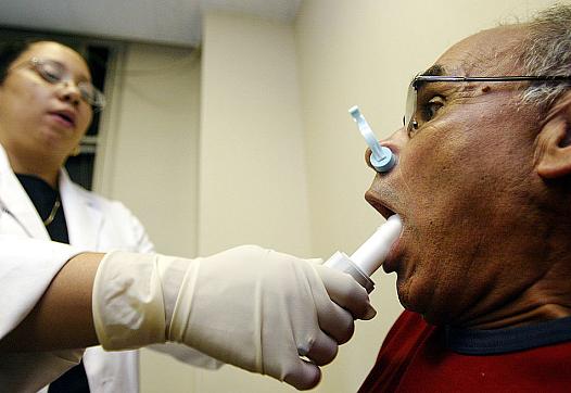 A man exposed to air pollutants near Ground Zero after Sept. 11 inhales deeply before blowing into a spirometer to check for air