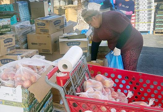 A volunteer packages peaches during a food distribution at Vida Life Ministries in Bloomington on July 16, 2022.