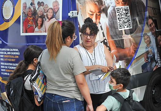 Riverside County Department of Public Social Services employee, Adriana Magana, talks with Diana Hernandez of Riverside regardin