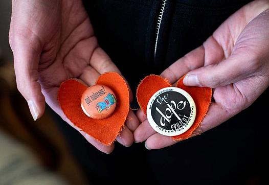 Rachel McLean holds two pins on orange fabric hearts from the memorial for Pete Morse, at her home on March 10, 2022.