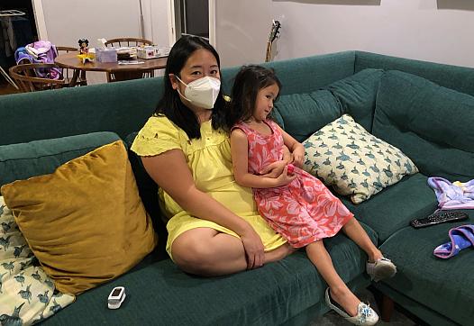 Anna Almendrala takes a short break from her oxygen concentrator to watch TV with her daughter, Marigold "Goldie" Ganz, three da